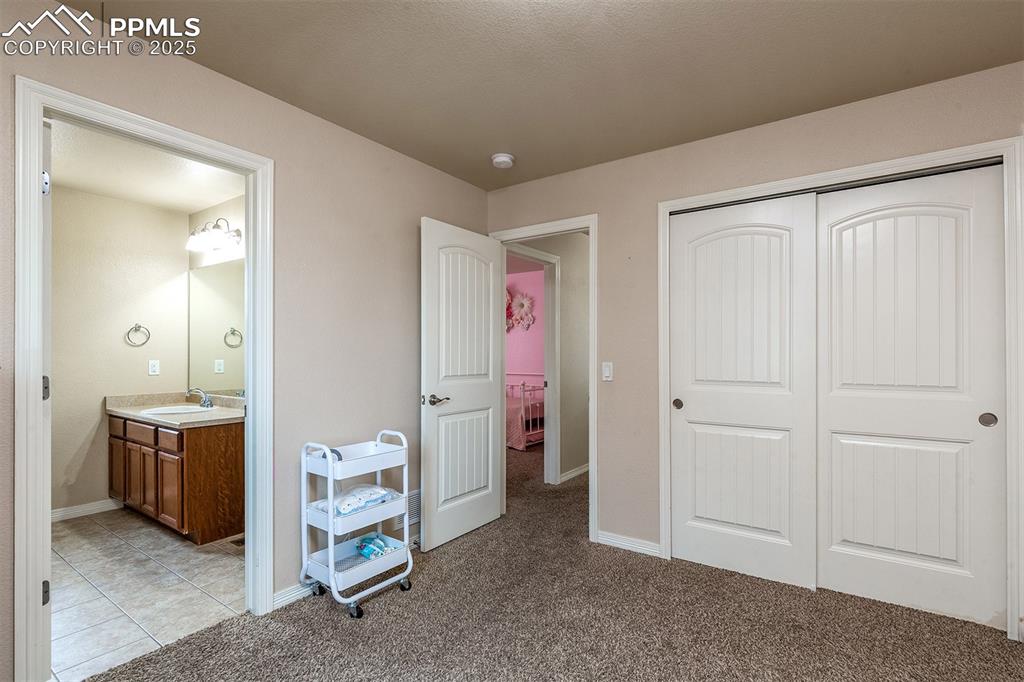 Image 23 of 33: Bedroom with a closet, light colored carpet, and ensuite bath