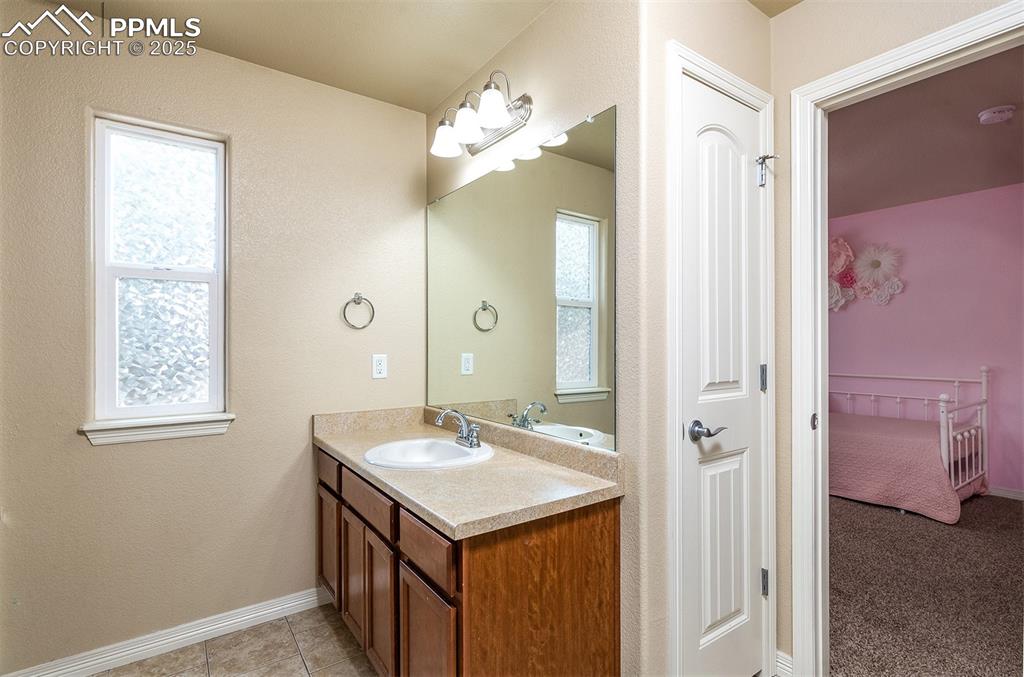 Image 24 of 33: Bathroom featuring vanity, plenty of natural light, and tile patterned floo