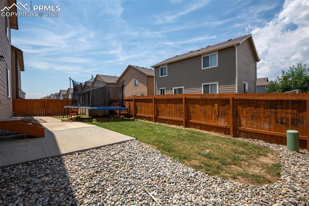 Image 33 of 33: Fenced backyard with a trampoline, a patio area, and a residential view
