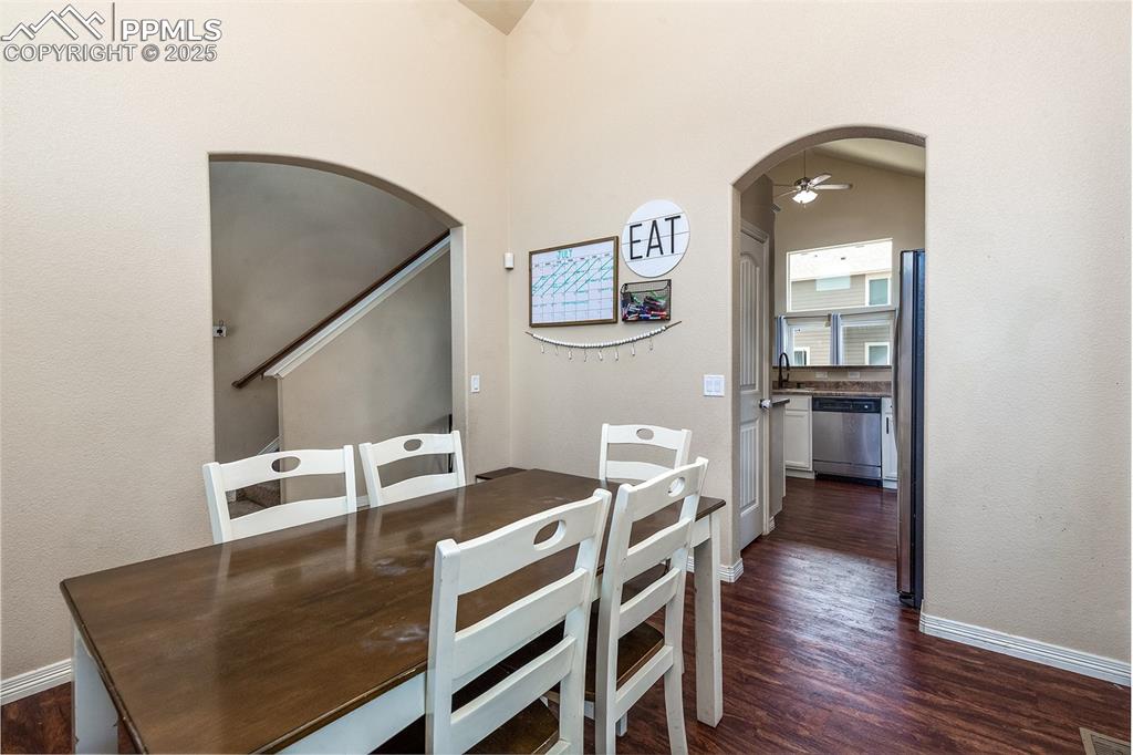 Image 6 of 33: Dining room with arched walkways, a ceiling fan, and dark wood-style floori