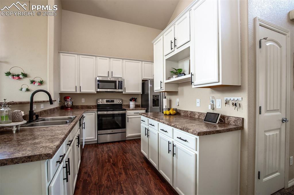 Image 7 of 33: Kitchen featuring dark countertops, stainless steel appliances, white cabin