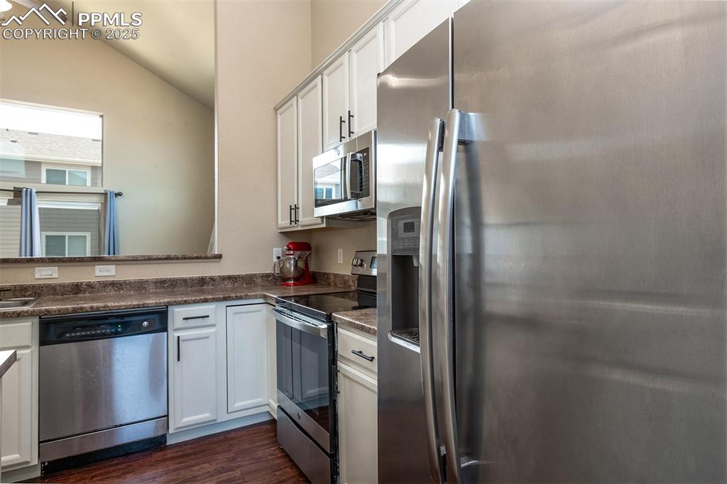 Image 8 of 33: Kitchen with appliances with stainless steel finishes, dark wood-style floo