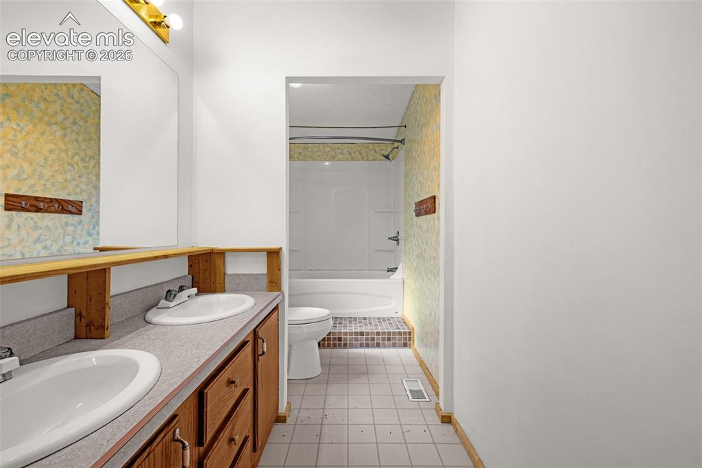 Image 11 of 27: Double vanity with wood-finish cabinetry and integrated sinks