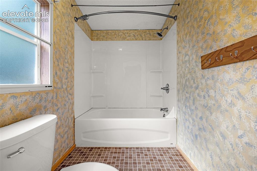Image 12 of 27: Bathtub and shower combination with white surround, chrome fixtures, and a