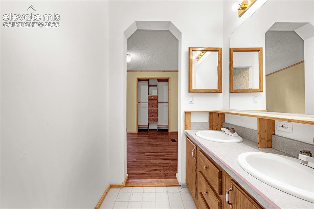 Image 13 of 27: Double vanity with integrated sinks, wood-finish cabinetry, and framed mirr