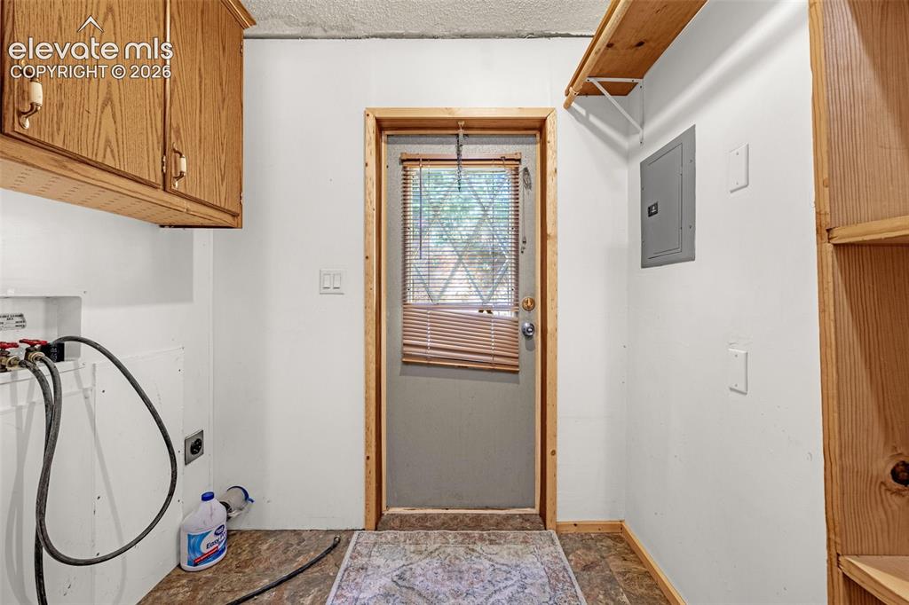 Image 15 of 27: Laundry area featuring wood-finish cabinetry, built-in shelving, and a util