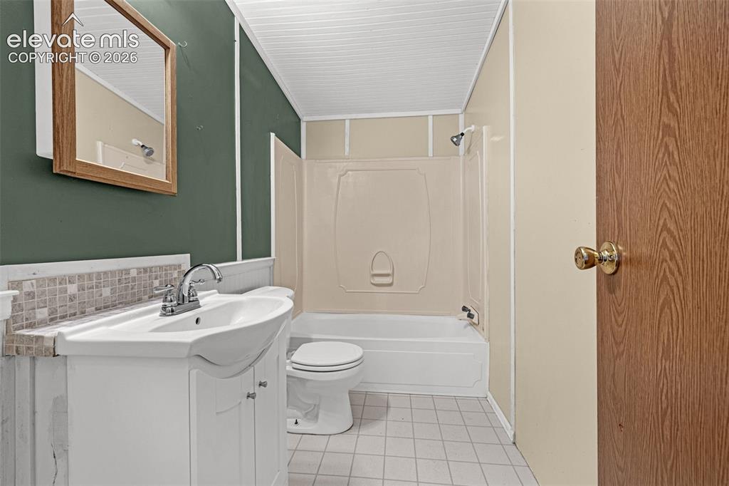 Image 19 of 27: White vanity with an integrated sink, mosaic tile backsplash, and a shower-