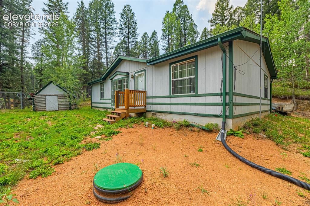 Image 2 of 27: Exterior residence with white siding, dark green trim, front porch with woo