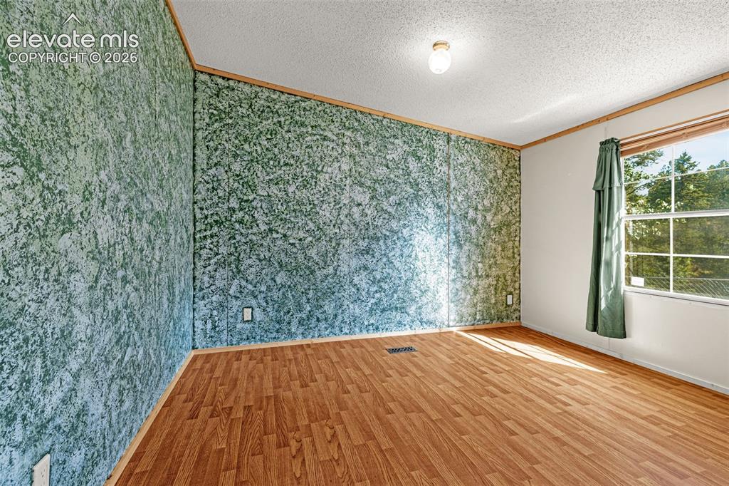 Image 20 of 27: Wood-finish flooring with a textured accent wall and flush-mount ceiling li