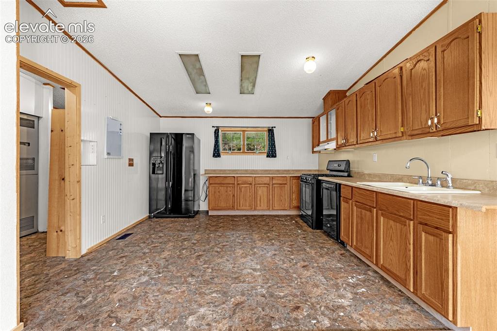 Image 7 of 27: Kitchen featuring wood-finish cabinetry, black appliances, a double basin s