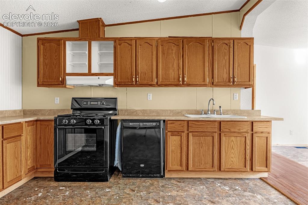 Image 8 of 27: Wood-finish cabinetry with a laminate countertop, a black gas range, and a