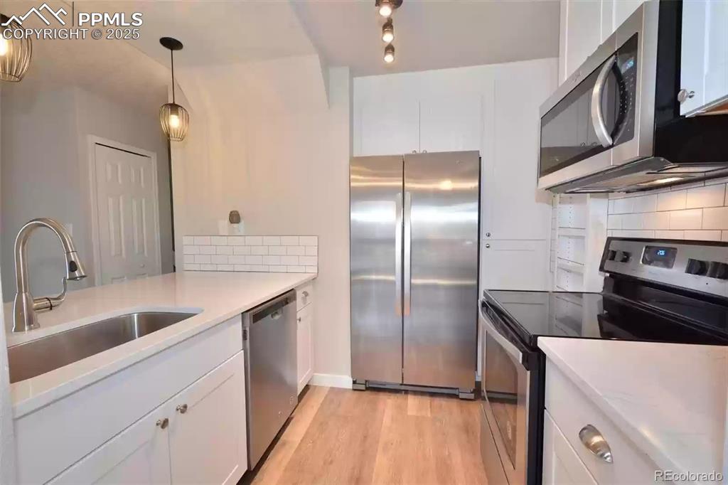 Image 10 of 28: Kitchen featuring appliances with stainless steel finishes, white cabinets,