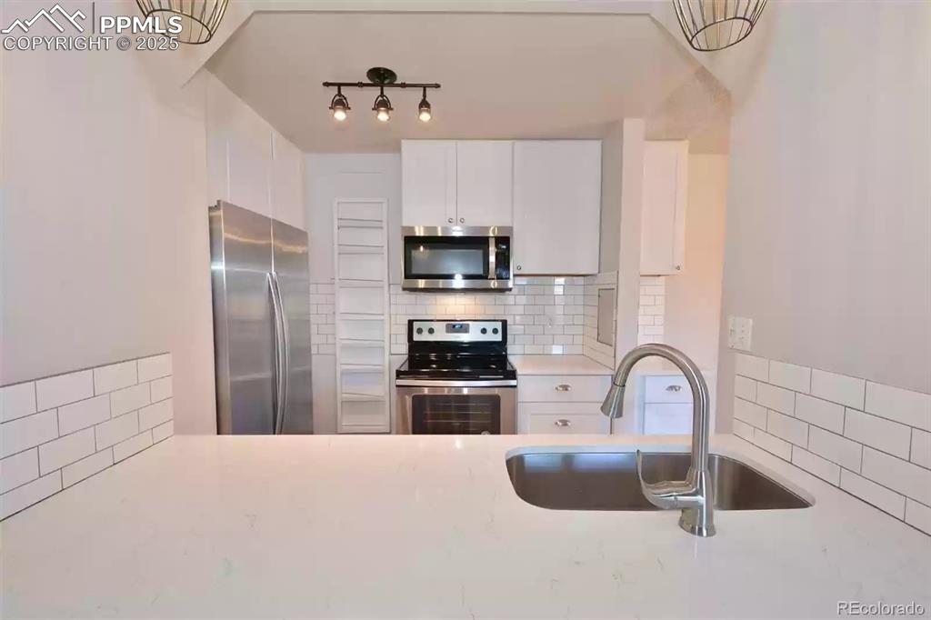 Image 11 of 28: Kitchen featuring tasteful backsplash, appliances with stainless steel fini