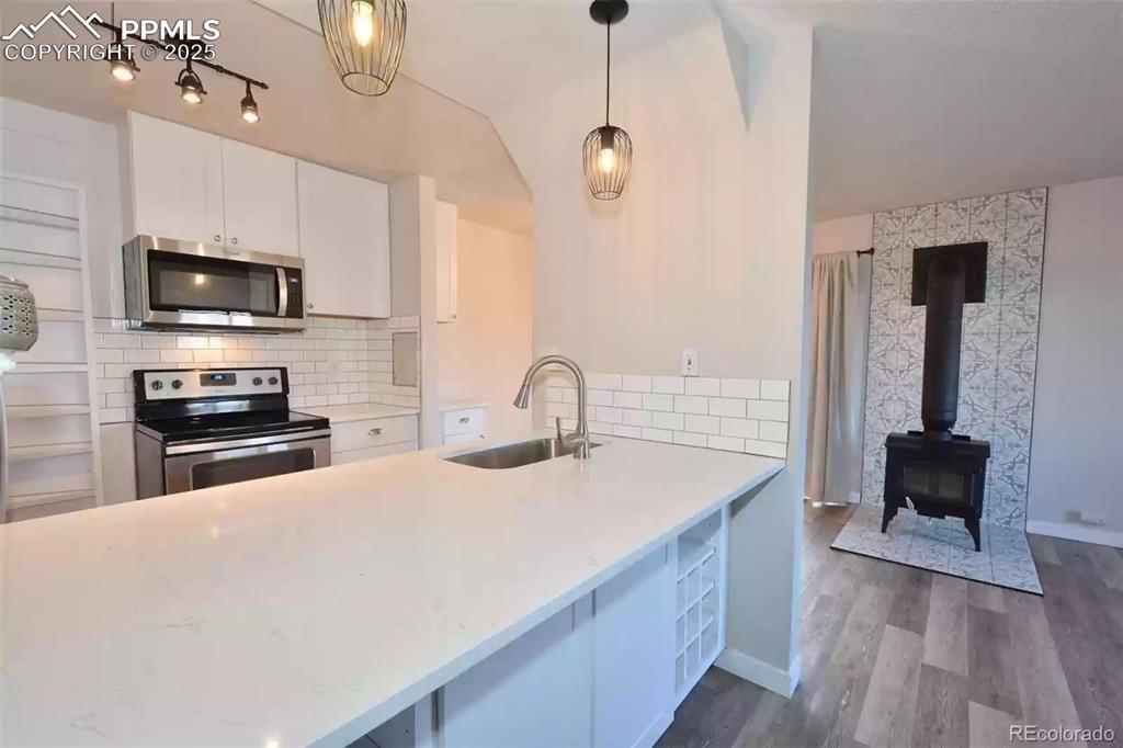 Image 2 of 28: Kitchen with backsplash, appliances with stainless steel finishes, white ca