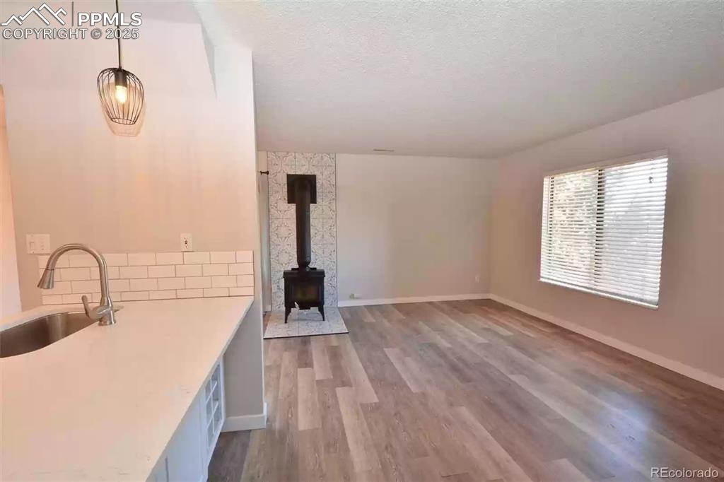 Image 3 of 28: Unfurnished living room featuring a wood stove, light wood-style flooring,