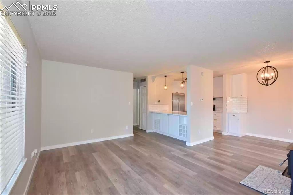 Image 6 of 28: Unfurnished living room with light wood-style floors, a chandelier, and a t