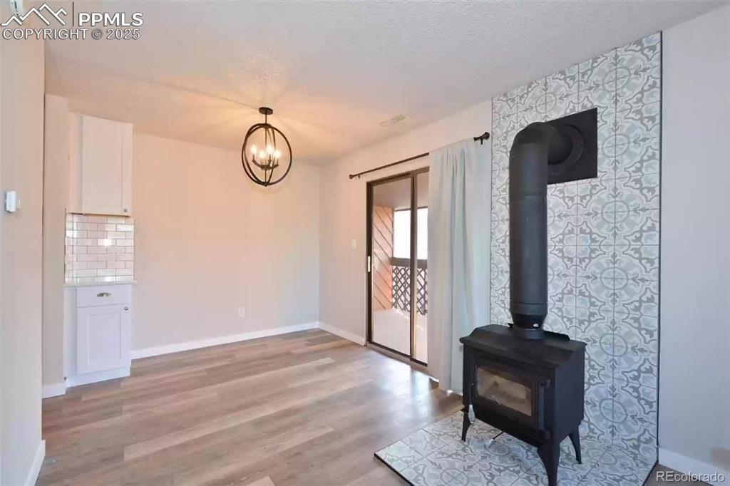 Image 7 of 28: Unfurnished dining area featuring a wood stove, light wood-style floors, an