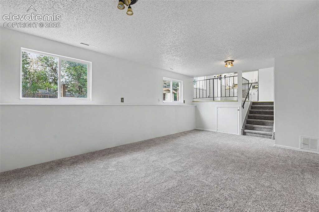 Image 13 of 32: Lower level family room with open flow to the kitchen and upper level livin