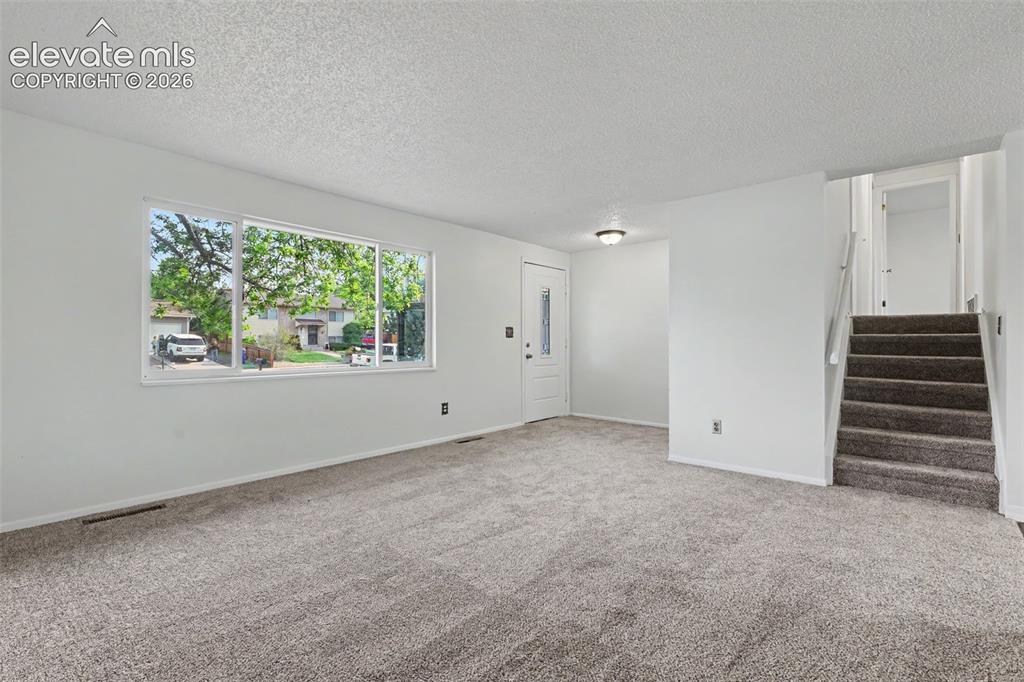 Image 3 of 32: Living room featuring the large front window and abundant natural light