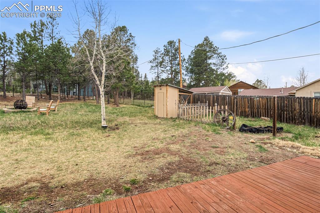 Image 23 of 31: Back yard with 6 ft fence, fire pit, chicken coop and storage shed
