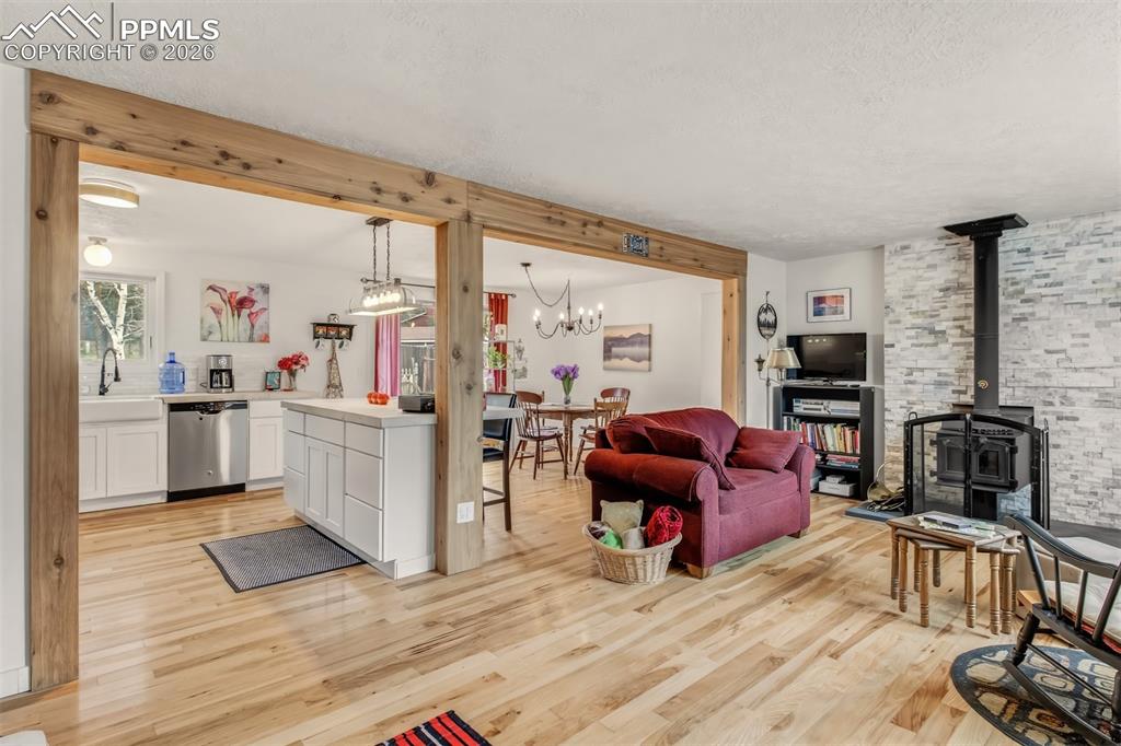 Image 5 of 31: Open concept living room with wood flooring, bay windows, and a wood burnin