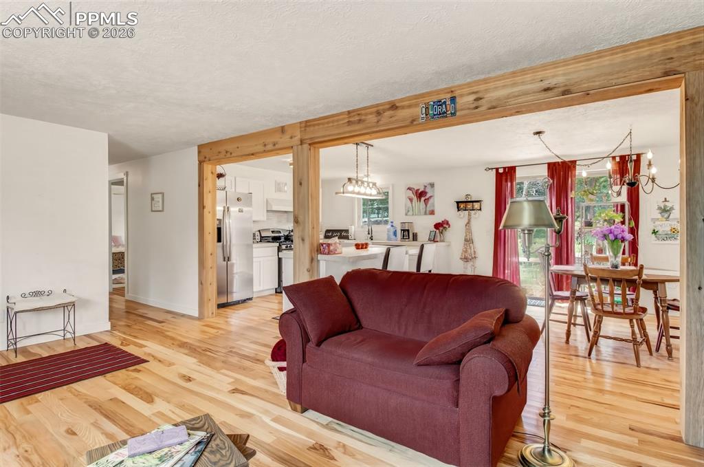 Image 6 of 31: Open concept living room with wood flooring, bay windows, and a wood burnin