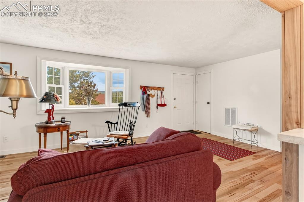 Image 7 of 31: Open concept living room with wood flooring, bay windows, and a wood burnin