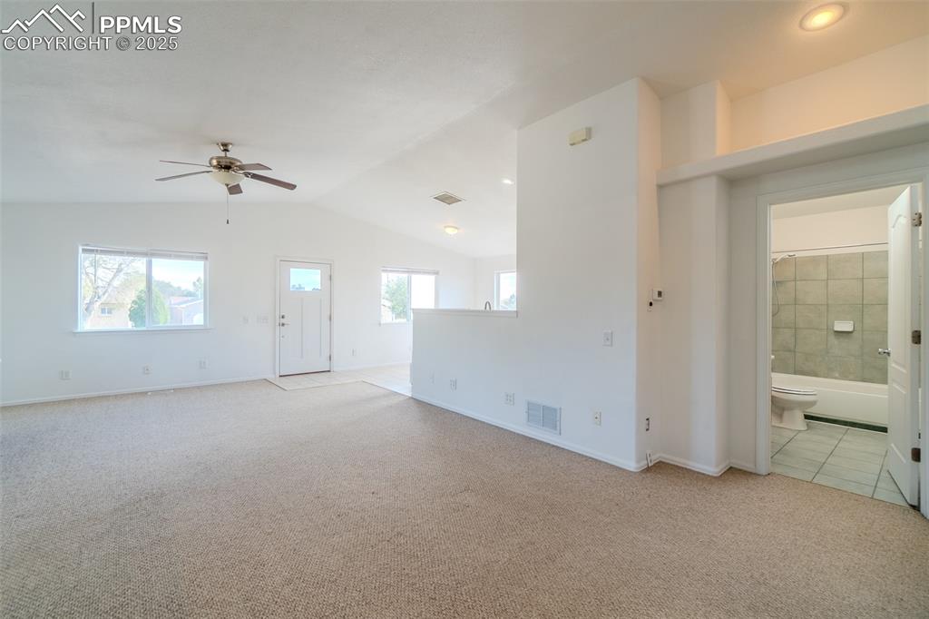 Image 10 of 36: Unfurnished living room with light colored carpet, lofted ceiling, and a ce