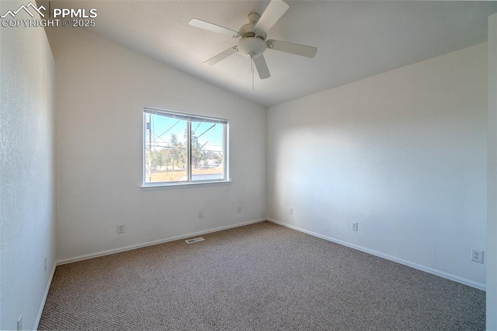 Image 14 of 36: Unfurnished room with lofted ceiling, carpet floors, and a ceiling fan