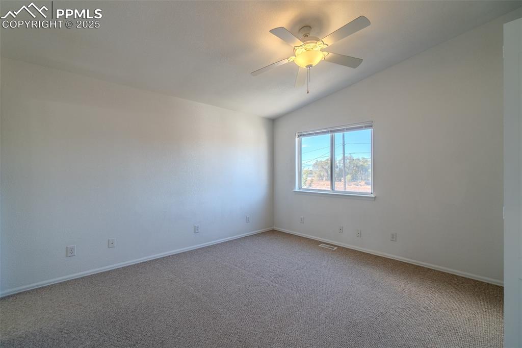 Image 15 of 36: Carpeted spare room with vaulted ceiling and a ceiling fan