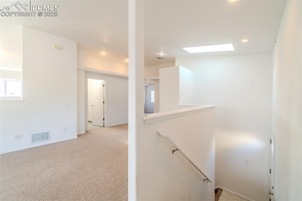 Image 23 of 36: Corridor with an upstairs landing, light colored carpet, recessed lighting,
