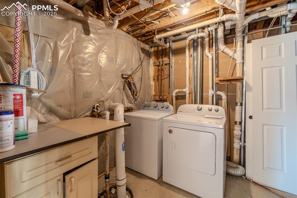Image 27 of 36: Laundry room with concrete flooring and washing machine and clothes dryer
