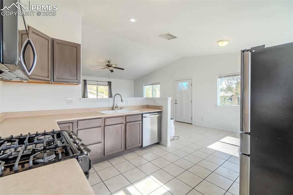 Image 3 of 36: Kitchen with stainless steel appliances, light countertops, light tile patt
