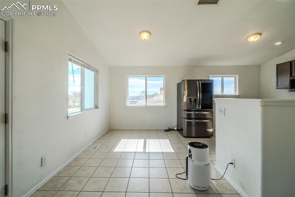 Image 35 of 36: Kitchen with light tile patterned floors, stainless steel fridge, and vault