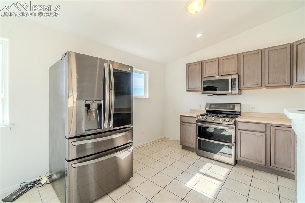 Image 4 of 36: Kitchen featuring appliances with stainless steel finishes, lofted ceiling,