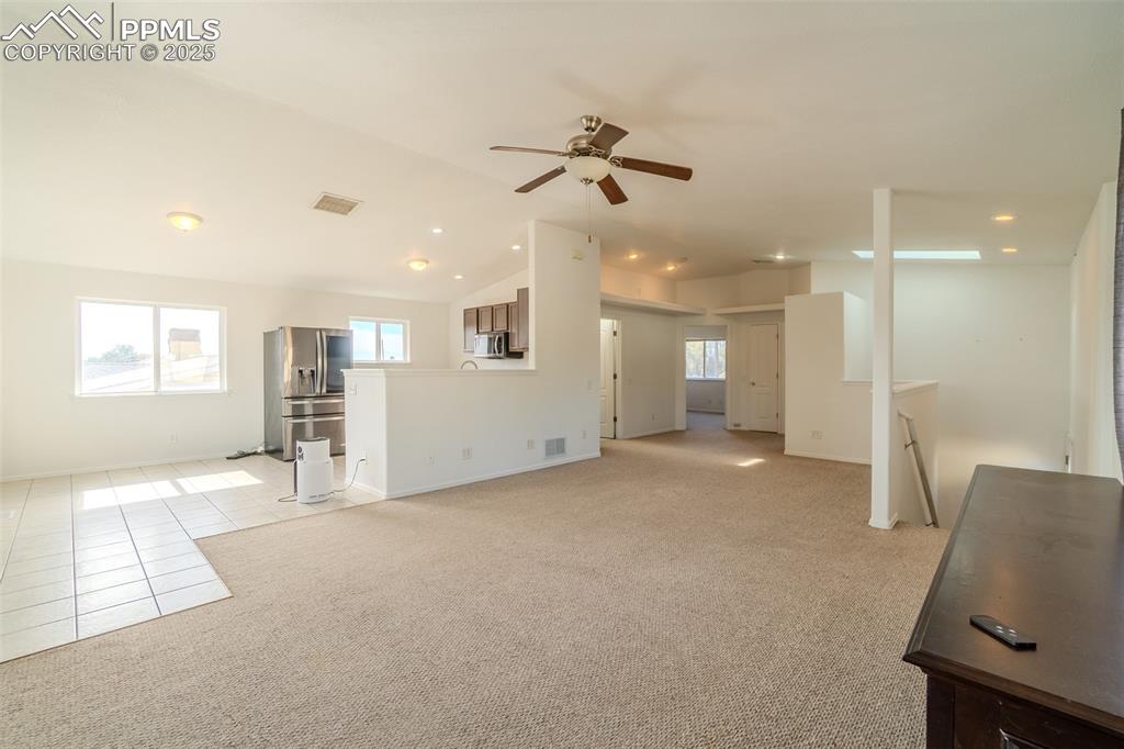 Image 7 of 36: Unfurnished living room featuring vaulted ceiling, light tile patterned flo