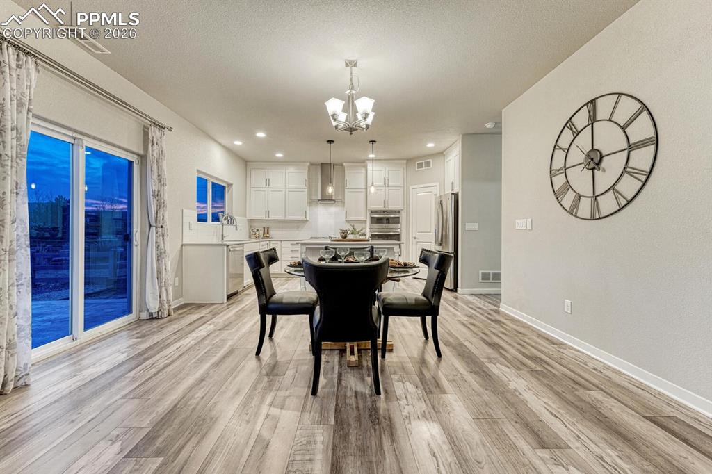 Image 10 of 50: Dining room with a chandelier and light wood-style flooring