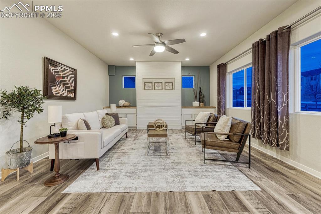Image 11 of 50: The living space includes a ceiling fan, light vinyl finished floors, and r