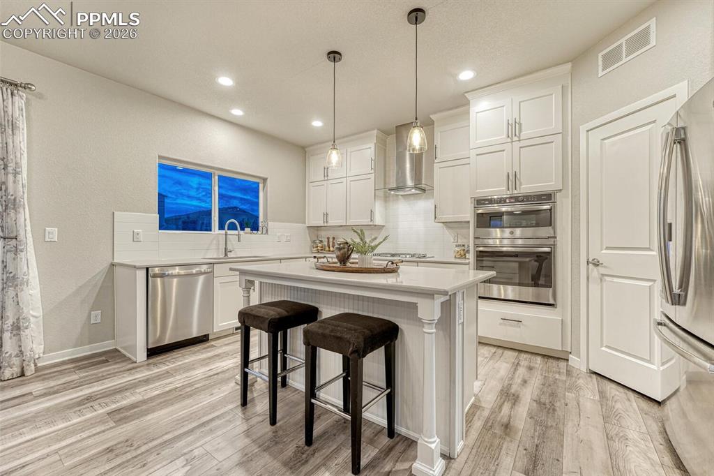 Image 17 of 50: Kitchen with white cabinetry, a kitchen bar, stainless steel appliances, a 