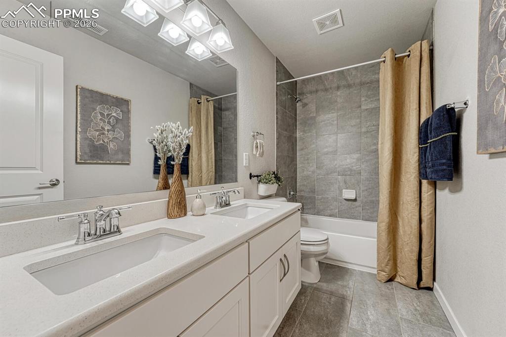 Image 27 of 50: Full bath featuring double vanity and shower / bath combination with curtai