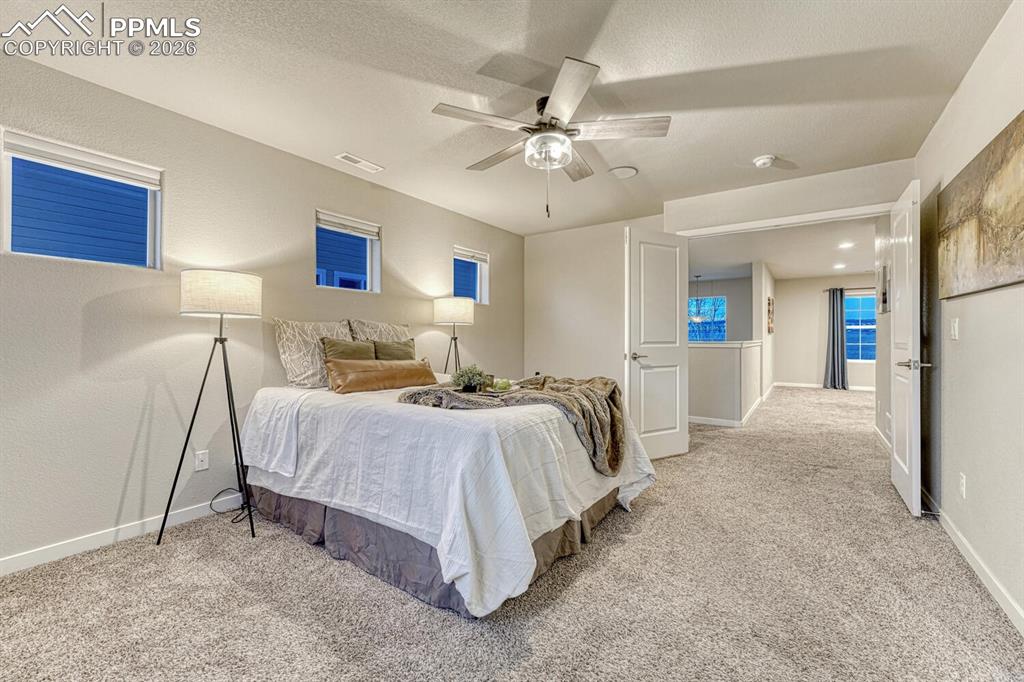 Image 33 of 50: Bedroom with ceiling fan, light colored carpet, and a textured ceiling