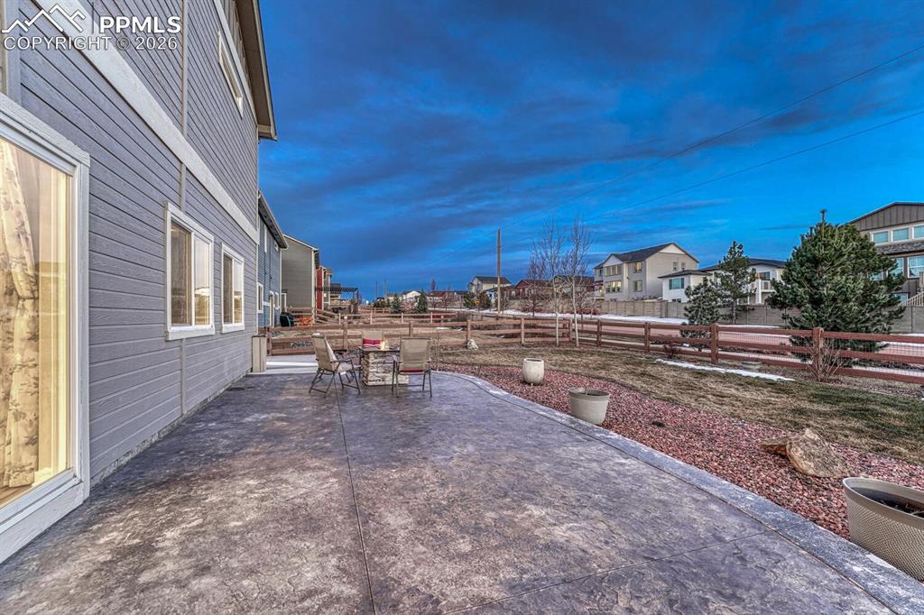 Image 39 of 50: Fenced backyard with a patio area, an outdoor fire pit, and a residential v