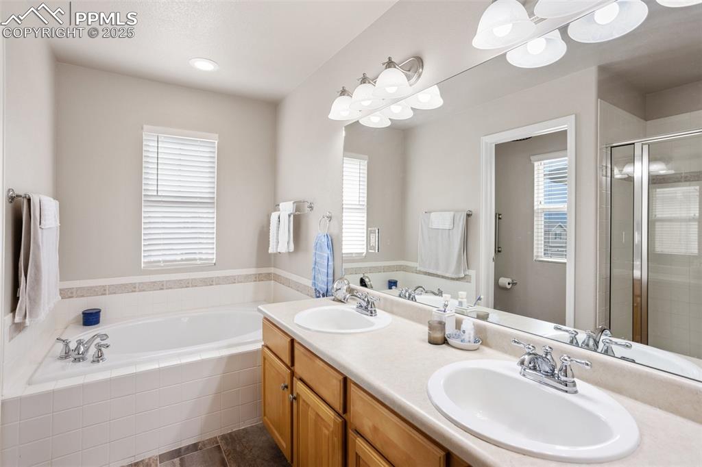 Image 14 of 26: Bathroom with a bath, a stall shower, double vanity, and tile patterned flo