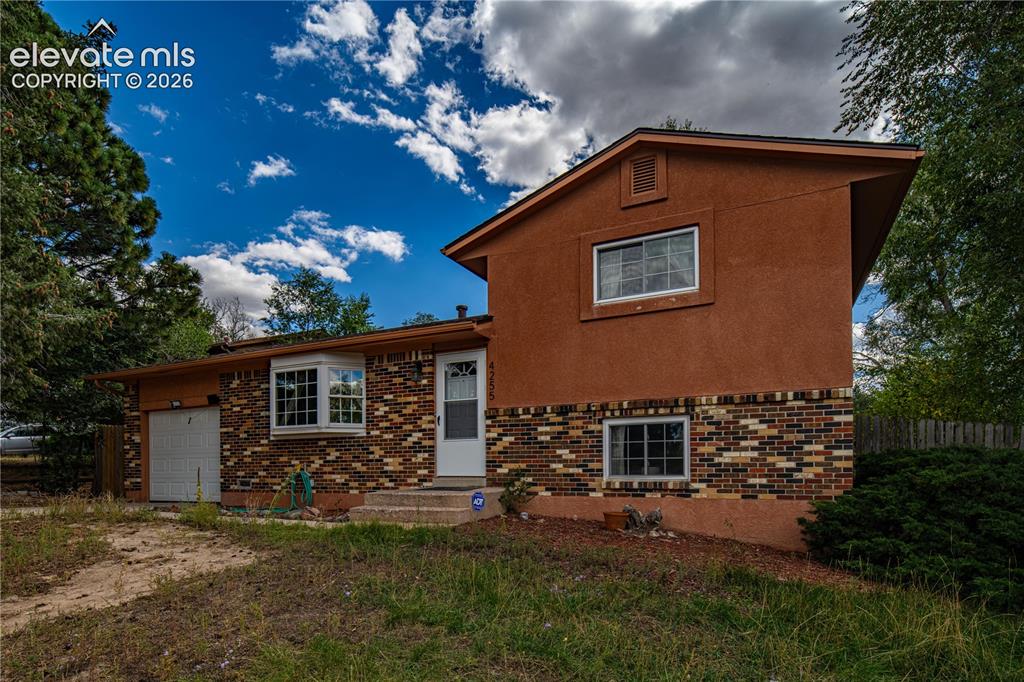 Image 1 of 9: Split-level residence featuring a brick and stucco exterior