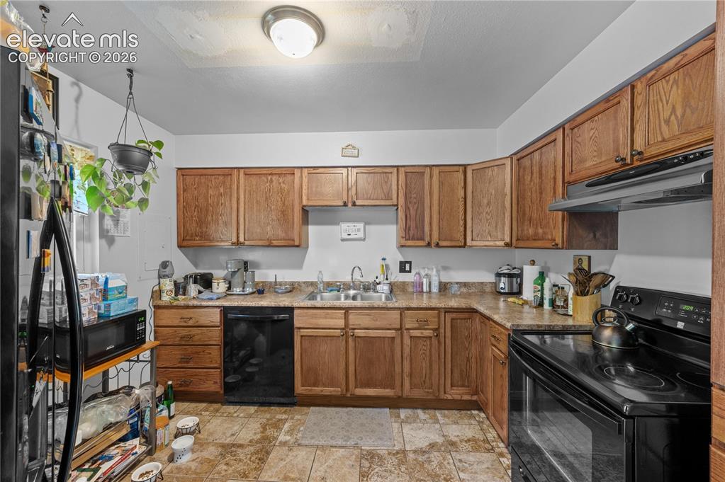 Image 4 of 9: Kitchen featuring wood cabinetry, stone-look countertops, and tile flooring