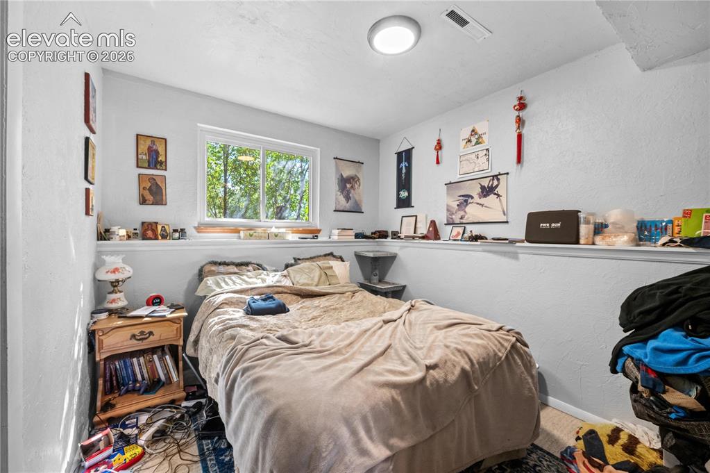 Image 7 of 9: Bedroom featuring a multi-pane window, white walls, and a built-in wall she