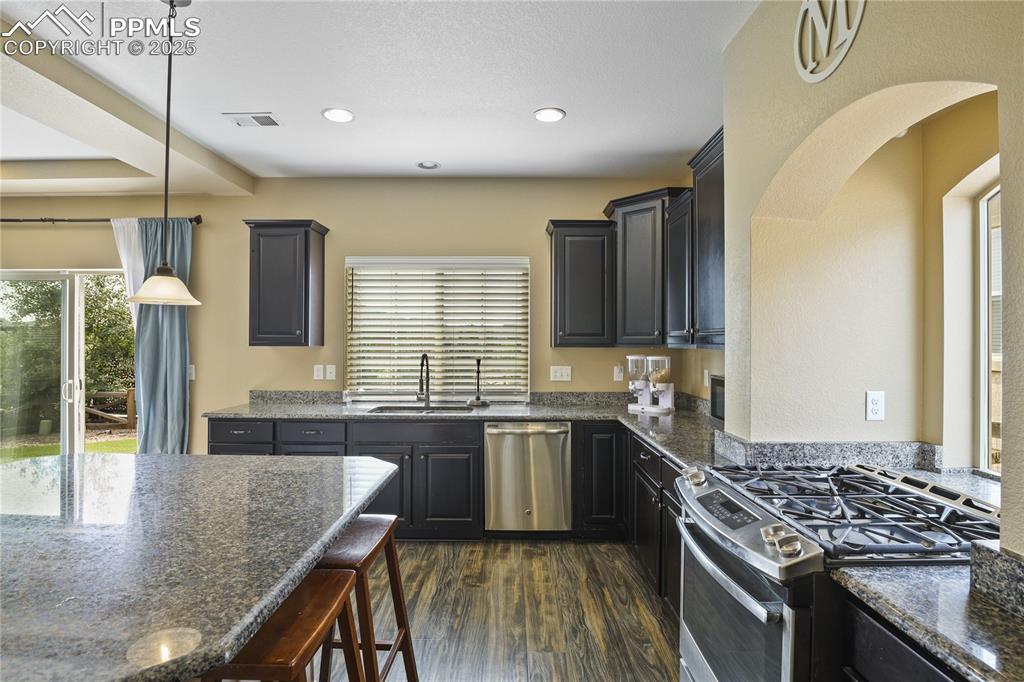 Image 13 of 38: Kitchen featuring stainless steel appliances, hanging light fixtures, dark