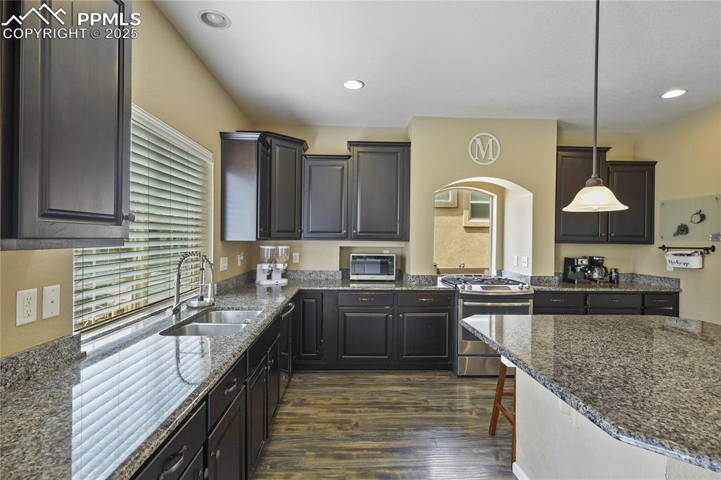 Image 14 of 38: Kitchen featuring a breakfast bar, dark wood-type flooring, sink, hanging l