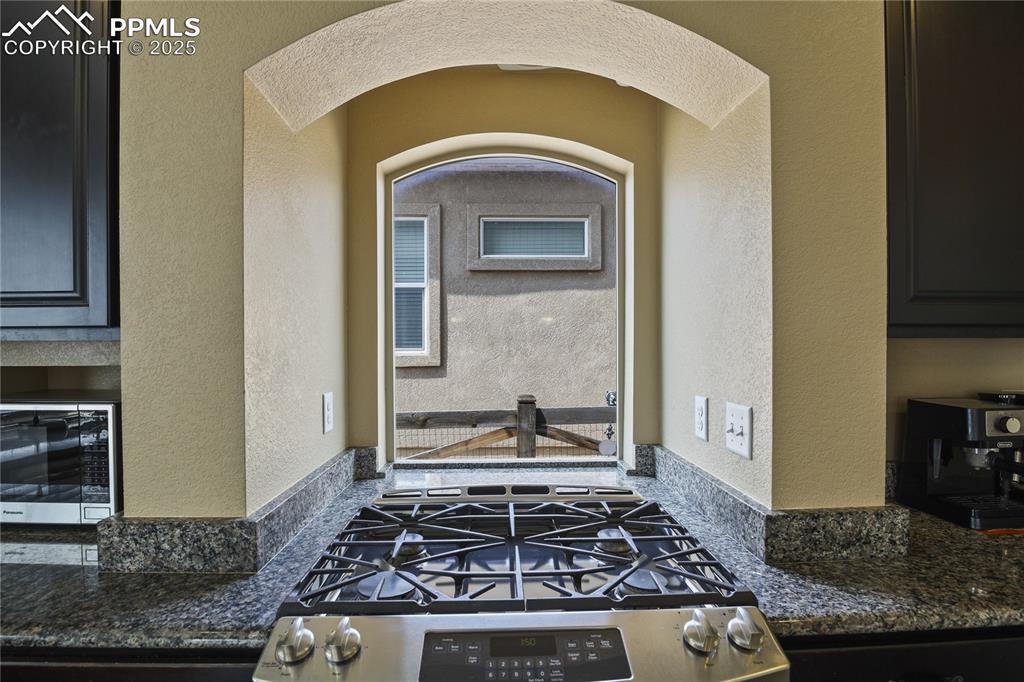 Image 15 of 38: Kitchen with dark stone counters and appliances with stainless steel finish