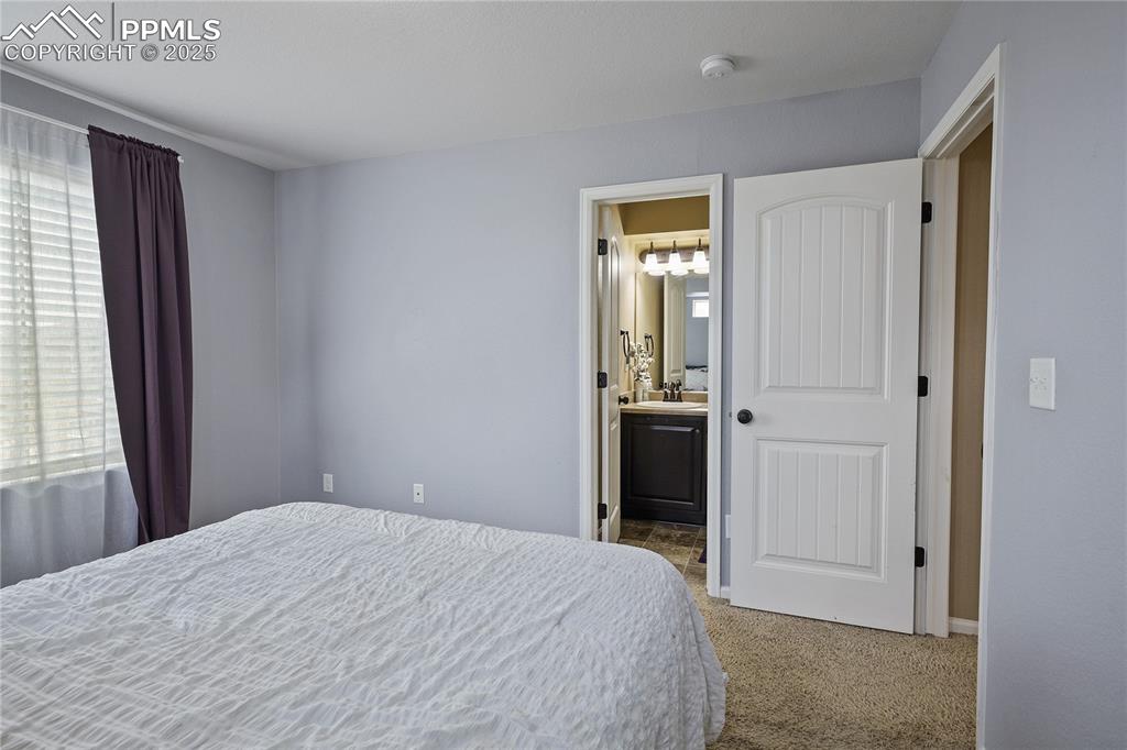 Image 24 of 38: Bedroom featuring connected bathroom, light colored carpet, and sink